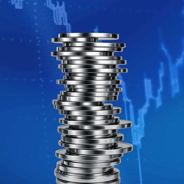 A stack of silver coins with a blue graph in the background